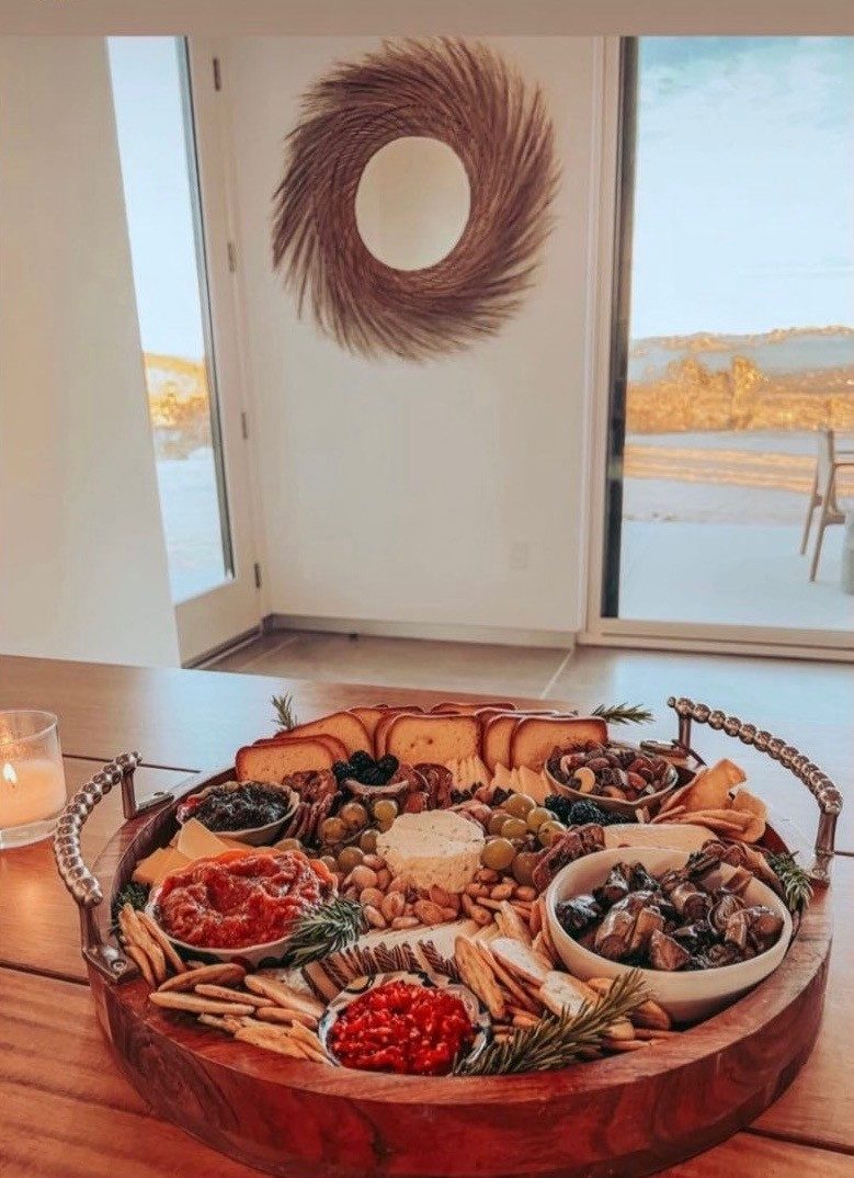 Round wood charcuterie board with cheese, meats, dips and crackers