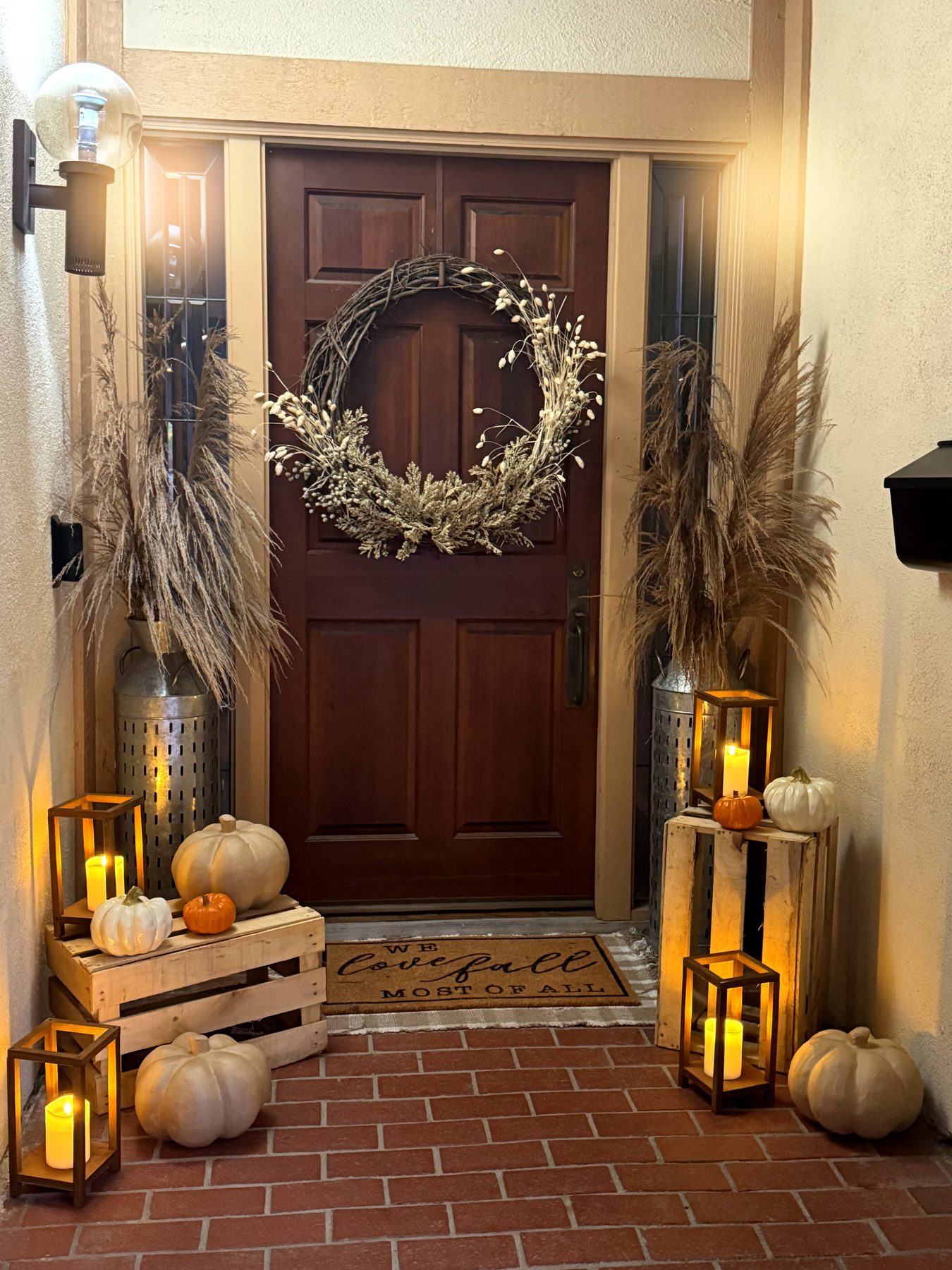 Front porch styling with wreath, mums and lit lanterns in the evening